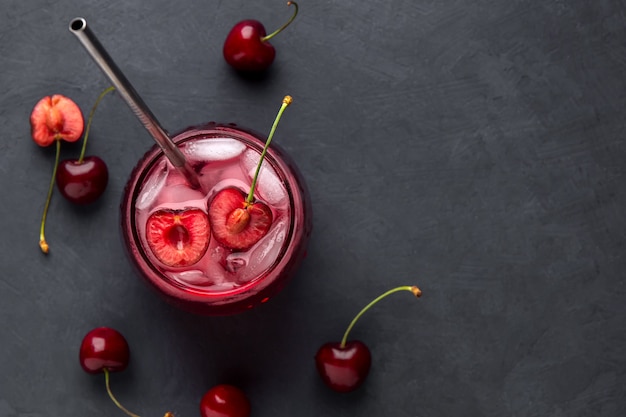 A refreshing drink with cherry and ice on a black background