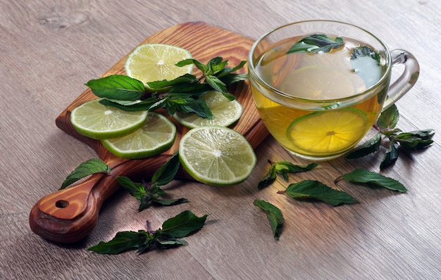 refreshing drink with mint and lime. a cup of mint tea with lime on a wooden table.