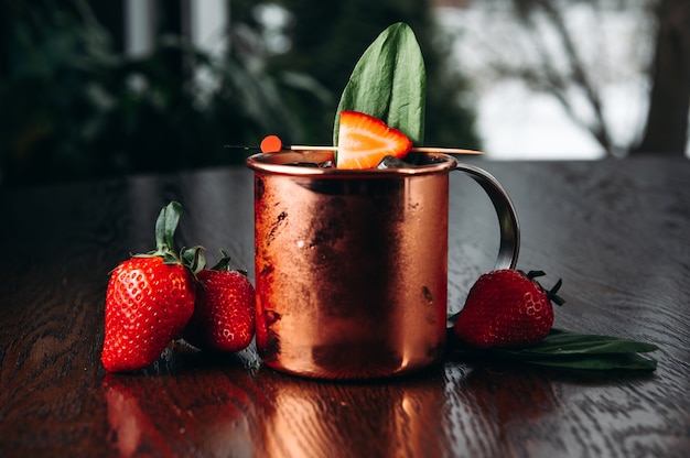 Refreshing iced Moscow mule alcoholic cocktail in copper mugs with strawberry