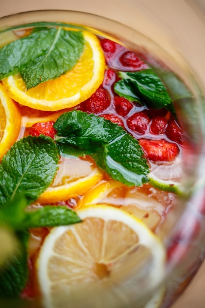 Refreshing lemonade with fresh fruit orange lemon cherry and mint leaves. Delicious non-alcoholic fruit cocktail in a jug