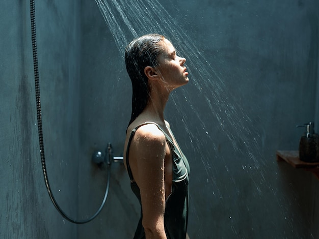 Refreshing morning shower with woman standing under flowing water in bathroom