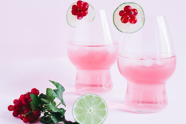 Refreshing pink berry lemonade with limes on a pink background