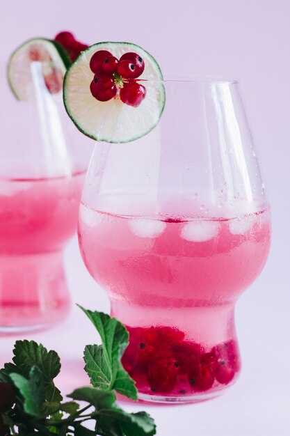 Refreshing pink berry lemonade with limes on a pink background