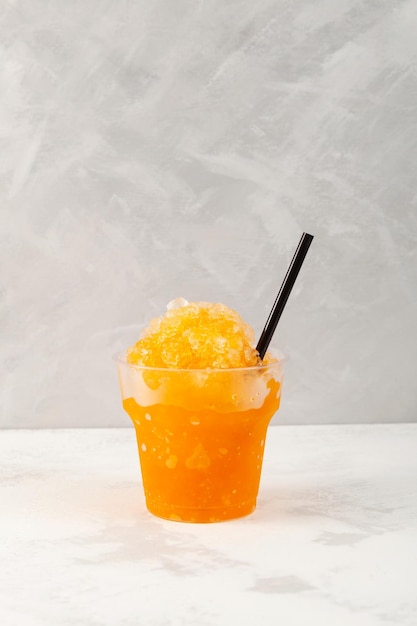 Refreshing Slushie drink in disposable plastic cup Orange Granizado Summer ice drink