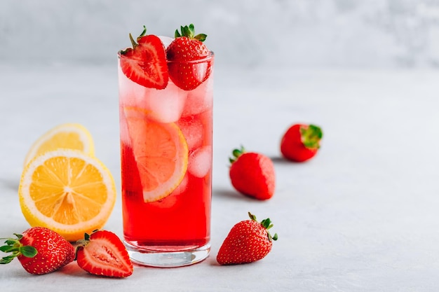 Refreshing Strawberry and lemon Iced Tea or lemonade in glass on a gray stone background