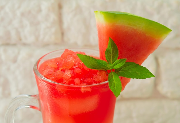 Refreshing watermelon smoothie in a glass and a leaf of mint on a black background Copy space