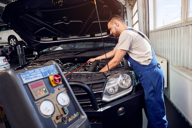 Photo refueling the air conditioner a mechanic pumps freon into the air conditioning system at a car service