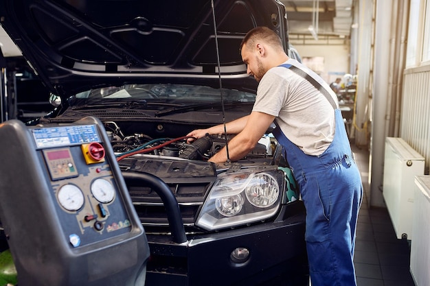 Photo refueling the air conditioner a mechanic pumps freon into the air conditioning system at a car service