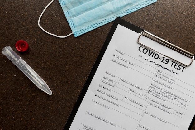 Registration form for coronavirus and a blood tube with face mask lyingsurface