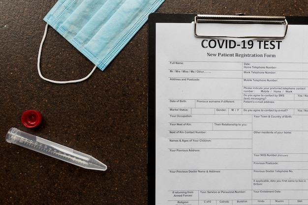 Registration form for coronavirus and a blood tube with mask lyingsurface