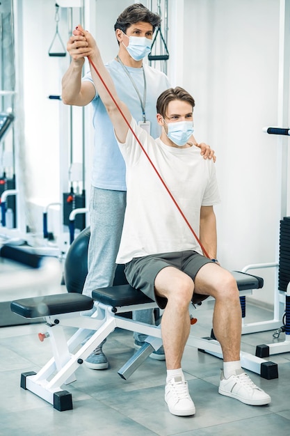 Rehabilitation Doctor and patient in protective masks having a workout in a rehabilitation center