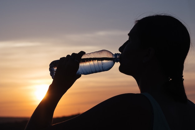 Rehydrate your body. Sporty woman drinking water outdoor on sunny day.