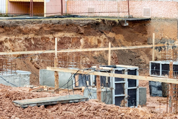 Reinforced concrete foundation of a modern monolithic residential building Prepared formwork with reinforcing mesh for pouring concrete Dirt and clay at the construction site