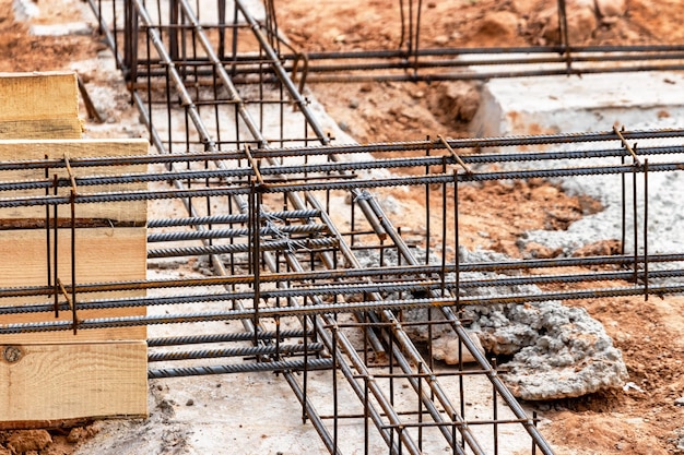 Reinforced concrete foundation of a modern monolithic residential building Prepared formwork with reinforcing mesh for pouring concrete Dirt and clay at the construction site