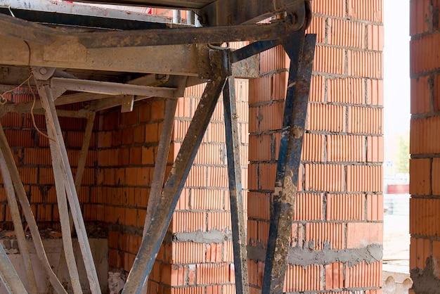 Reinforced scaffolding for the work of masons in the construction of brick walls Apparel for work on the construction site and storage of materials Closeup Construction of brick walls