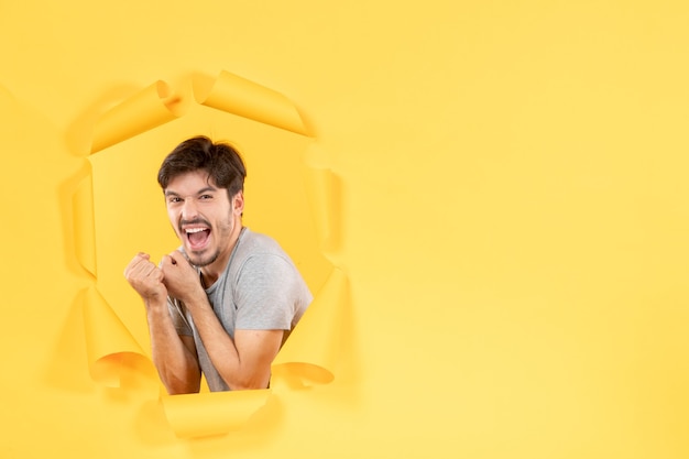 rejoicing young male on torn yellow paper background facial indoor guy handsome