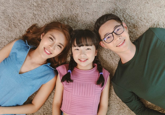 Relax Asian family laying with happy and smile on carpet in living room at home. top view