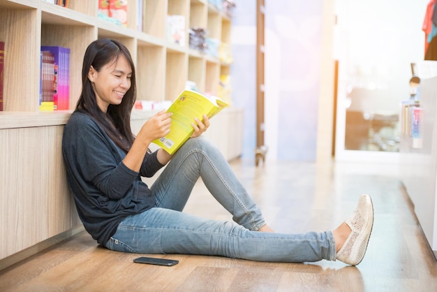 Relax asian woman reading book sitting on sofa in living room holding book to read Young woman relaxation reader reading open book leisure mind Happiness beauty woman person smiling face happy time