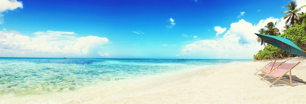 Relax on tropical beach in the sun on deck chairs under umbrella