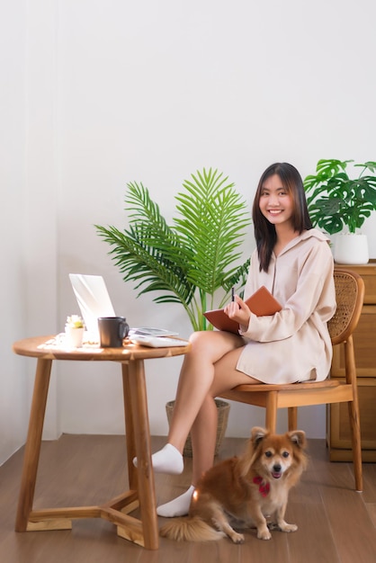 Relaxation lifestyle concept Asian woman writing on notebook while sitting in living room with dog