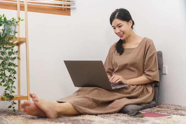 Relaxation lifestyle concept Young Asian woman using laptop to surf social media in living room