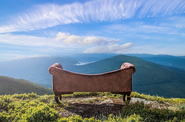 Relaxation in nature a classic sofa on top of a mountain against the background of a mountain landscape on a warm summer day the sky is blue with clouds