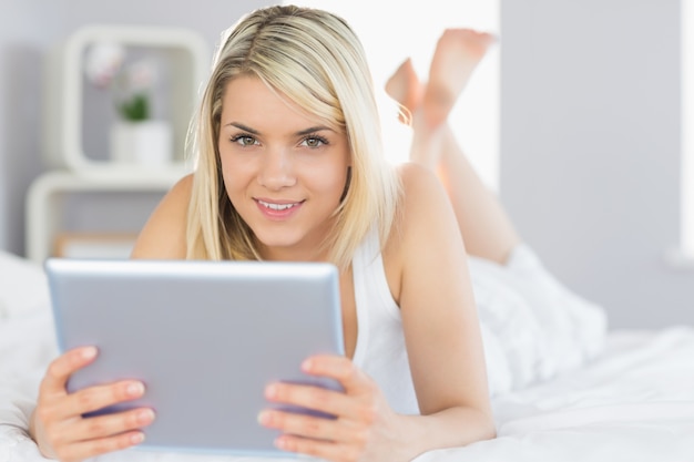 Relaxed beautiful woman using digital tablet in bed