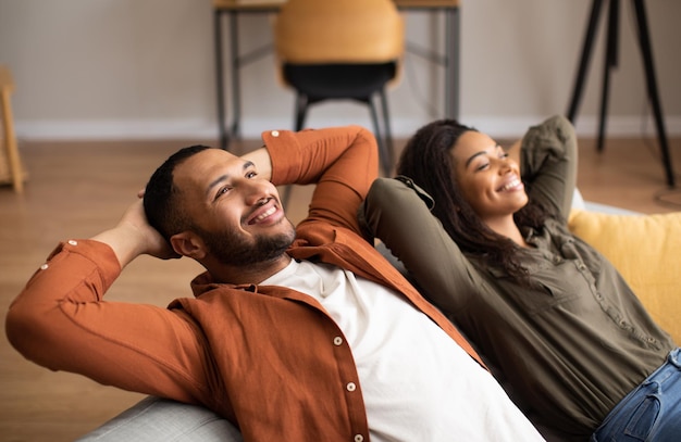 Relaxed Black Couple Sitting On Couch Relaxing Together At Home