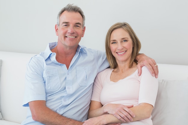 Relaxed couple sitting on sofa with arm around