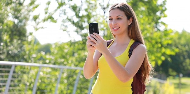 Relaxed female hiker checking her smart phone.