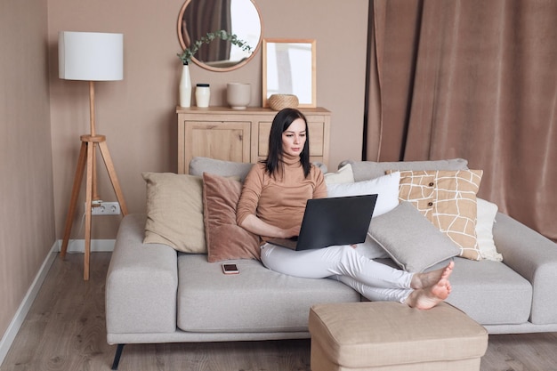 Relaxed female on sofa with laptop working at home