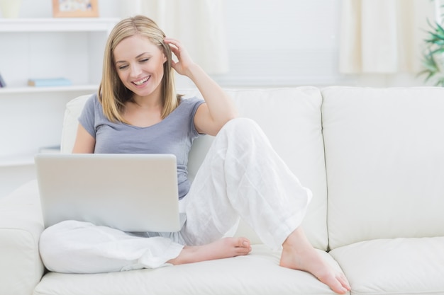 Relaxed happy woman using laptop on sofa