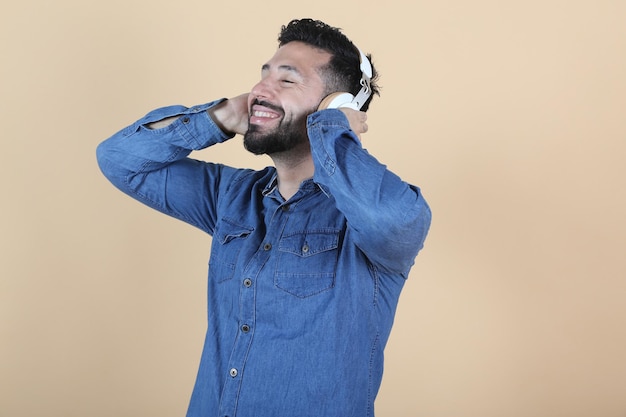 Relaxed hispanic latino man listens to music with headphones on yellow background