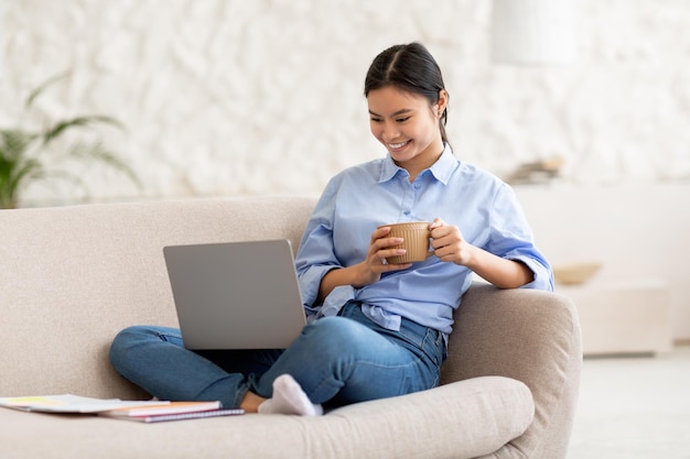 Relaxed japanese woman watching movie online using laptop