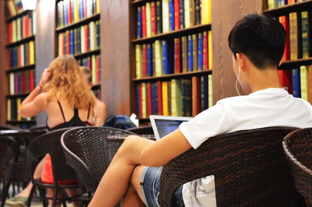 The relaxed lifestyle of asian men using laptop and smartphone in library.