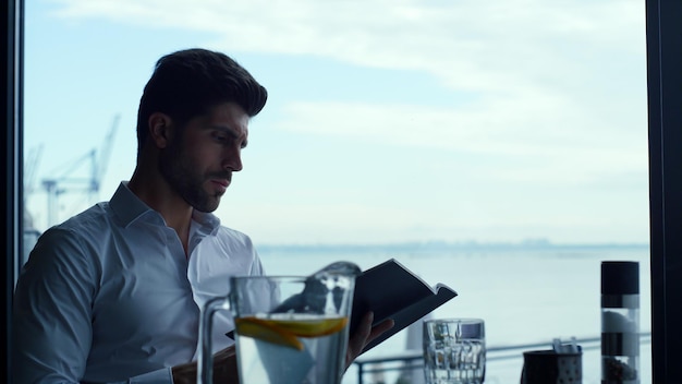 Relaxed man customer reading wine list in panoramic luxury lounge bar portrait