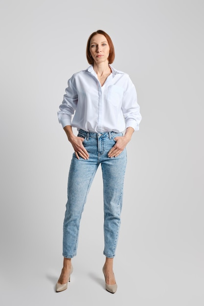 Relaxed middle aged woman wearing white shirt and blue jeans