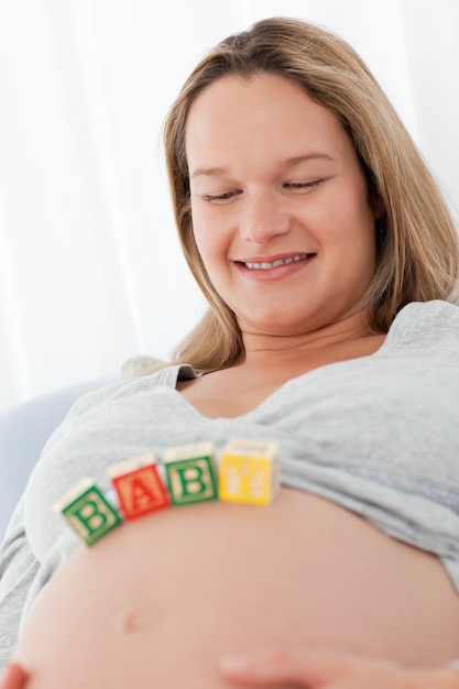 Relaxed woman looking at baby letters on her belly and resting