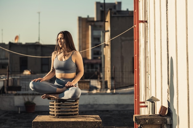 Photo relaxed woman practicing yoga meditating on a rooftop terrace.
relaxed woman practicing yoga stretching exercise on a rooftop terrace.