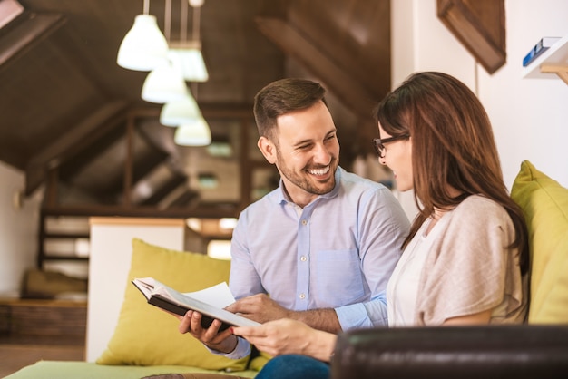 Relaxed young couple reading book on couch at home