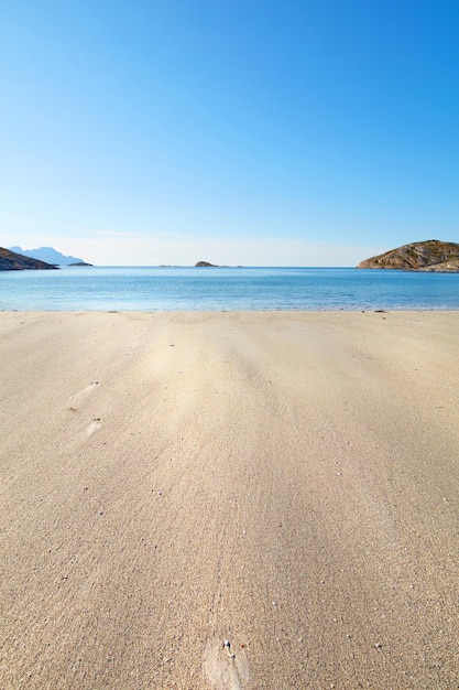 A relaxing beach on a summer day ideal for vacation Calm blue ocean beige sands with islands in the background An isolated coast in the city of Bodoe north of the Polar Circle