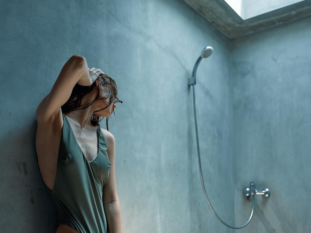 Relaxing in style woman in bathing suit leaning against wall in bathroom with shower