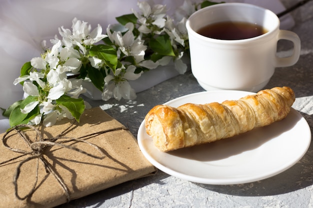 Relaxing time and happiness with cup of tea with among fresh spring flower. Morning tea with a cake on a warm sunny day.