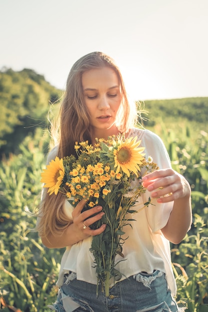  Relaxing young woman with lowers in nature, in corn, sunflower field