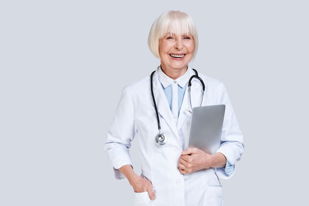 Reliable cardiologist. Beautiful senior woman in lab coat looking at camera and smiling 