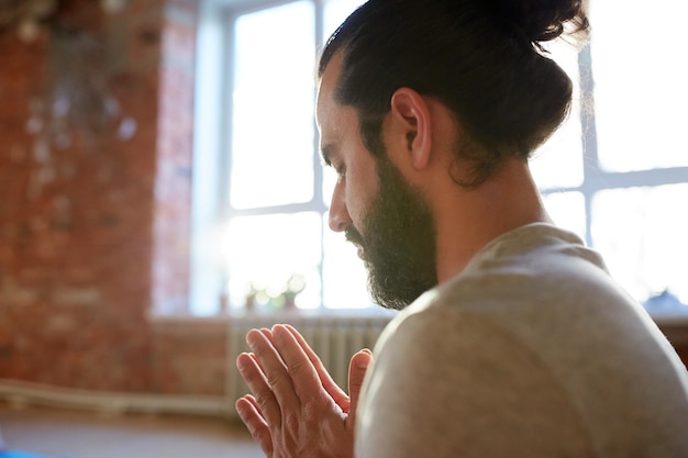 Photo religion, faith and people concept - close up of woman meditating or praying at yoga studio