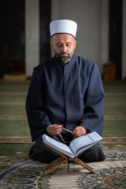 Photo religious muslim man reading a quran while praying inside the mosque.