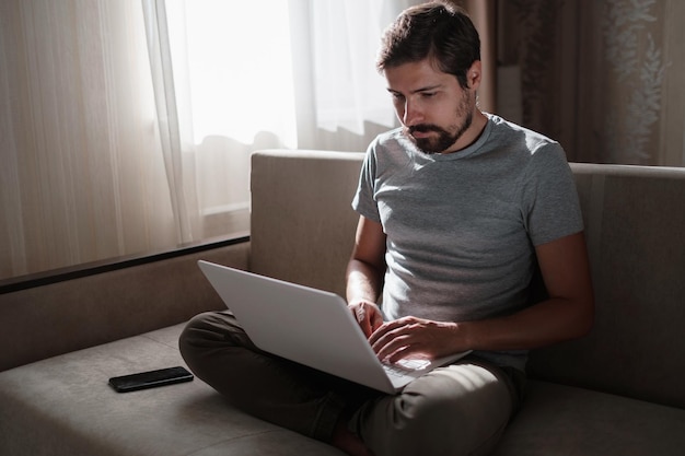 Remote Job Man Working On Laptop Sitting On Sofa At Home