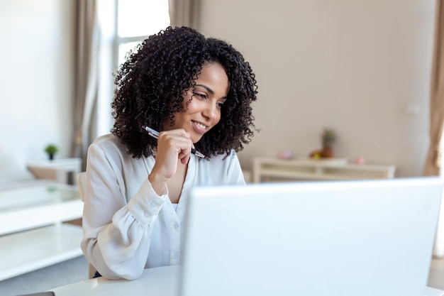 Remote job technology and people concept happy smiling young business woman with laptop computer and papers working at home office during the Covid19 health crisis