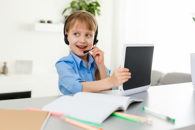 Remote lessons. The child smiles happily and gets knowledge remotely. Little girl study online learning from home. Online school.